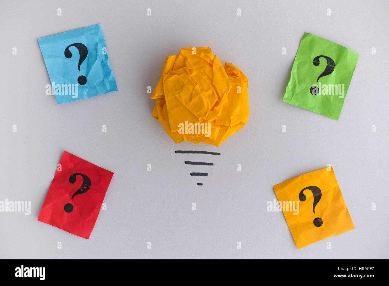 Auf der Suche nach neuen Ideen und Innovationen. Gelbe zerknittertes Papier Ball als eine Glühbirne und bunten Fragezeichen. Stockfoto