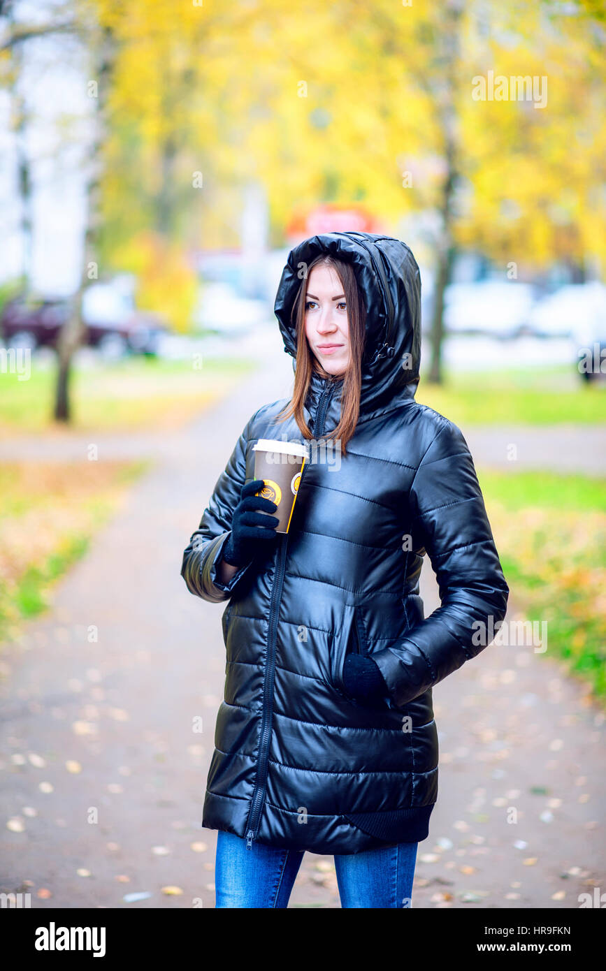 Mädchen im Herbst oder Frühjahr in einer schwarzen Jacke mit einem Kaffee  oder Tee in der Hand, im Freien. In der Stadt ruhen. Life Style.  Business-Frau in der Haube Stockfotografie - Alamy