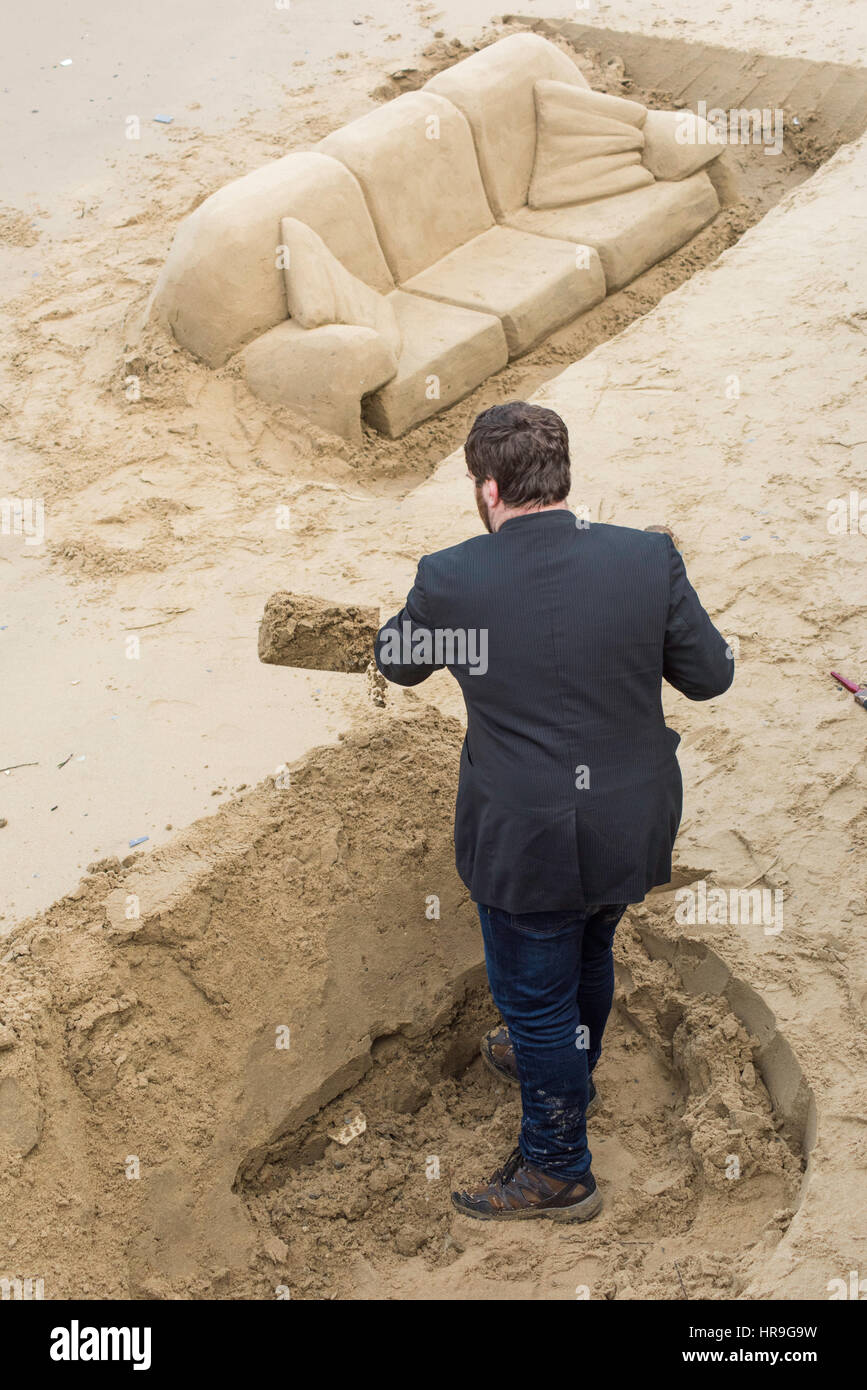 Ein Mann wie ihr Sand Graben Graben schafft Skulpturen an einem Strand auf der South Bank in London. Stockfoto