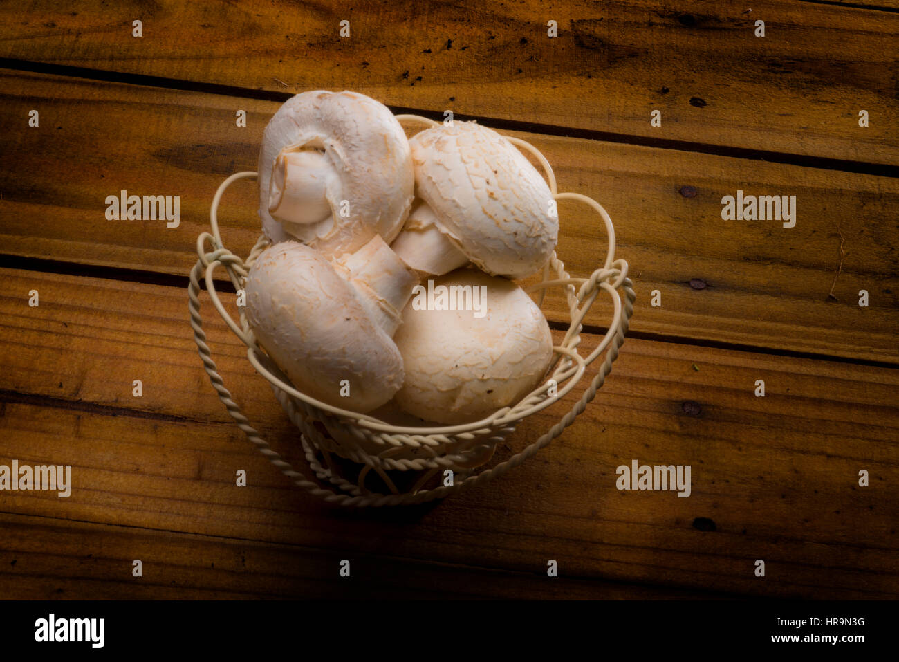 Draht-Korb voller weißer Pilze auf Holz Tisch Stockfoto