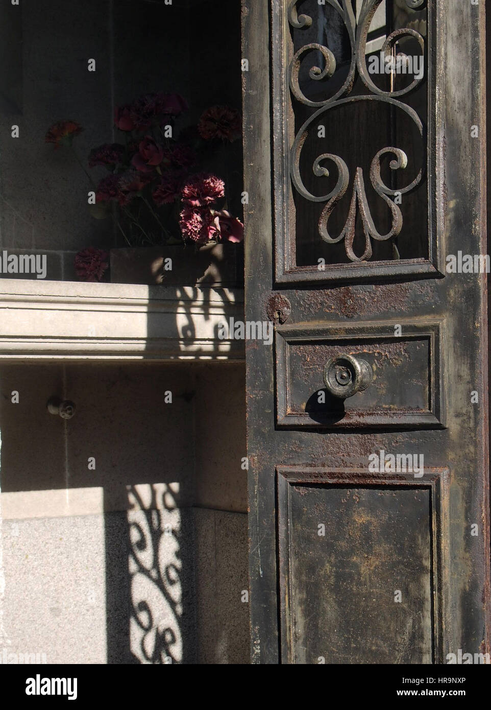 Eine schmiedeeiserne Grab Tür offen mit sterbenden Blumen am Friedhof Pere Lachaise in Paris, Frankreich. Stockfoto