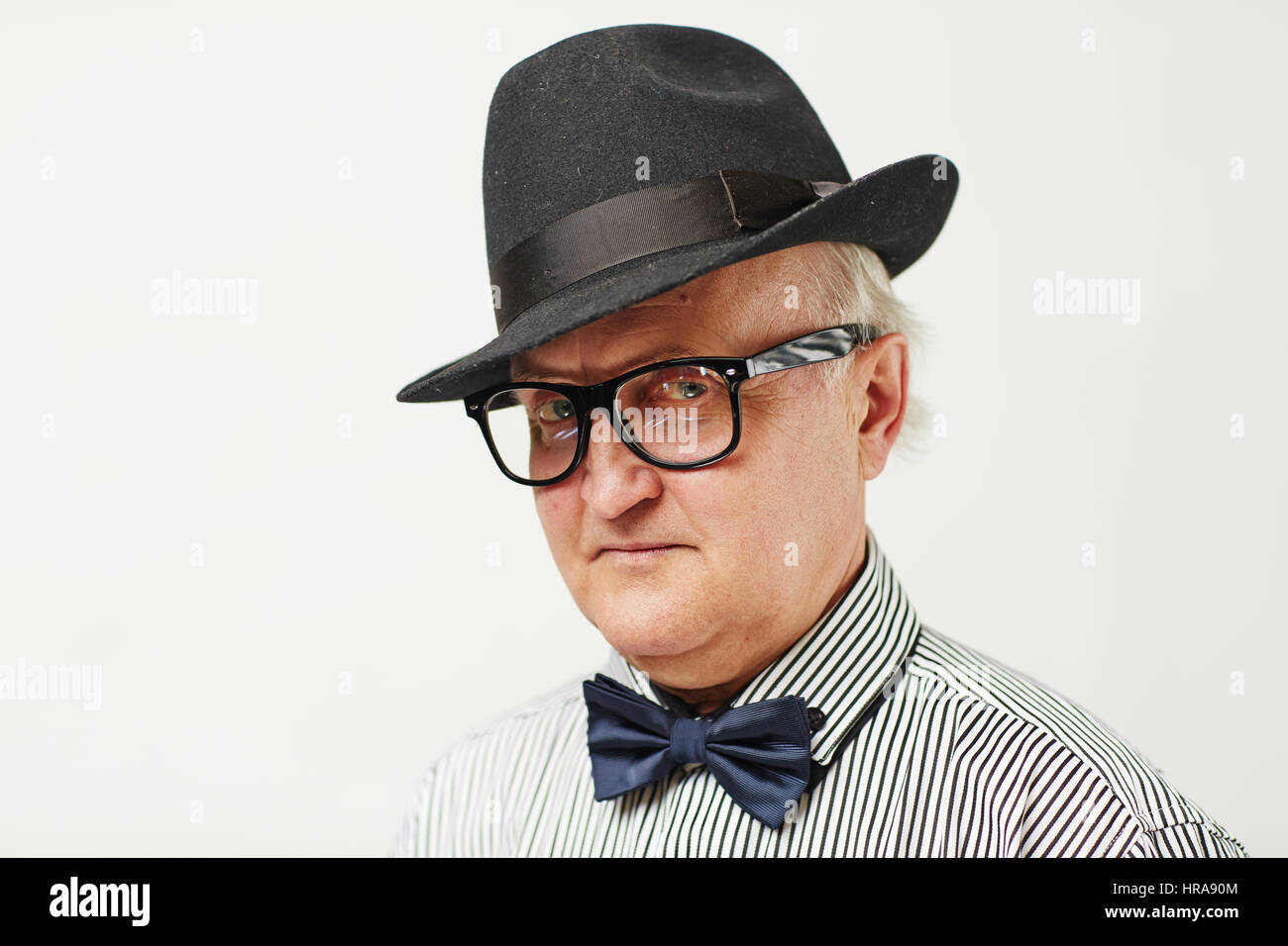 Porträt von Ernst älterer Mann mit schwarzem Hut und Fliege Blick in die Kamera durchdringend, Argwohn und Misstrauen zeigen Stockfoto