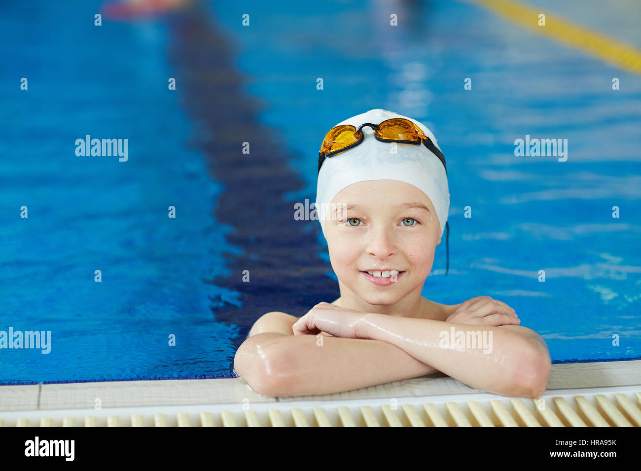 Porträt von niedlichen energetische Kind lächelnd zu Kamera am Rand des Pools beim Schwimmunterricht Stockfoto