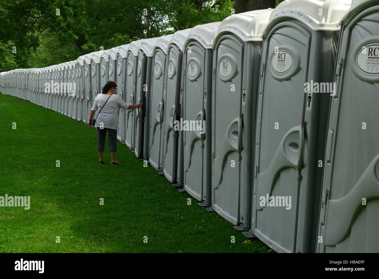 Eine Dame geht in eine sehr lange Folge von mobilen Toiletten im Parc LaFontaine in Montreal während der Montreal-Marathon Stockfoto