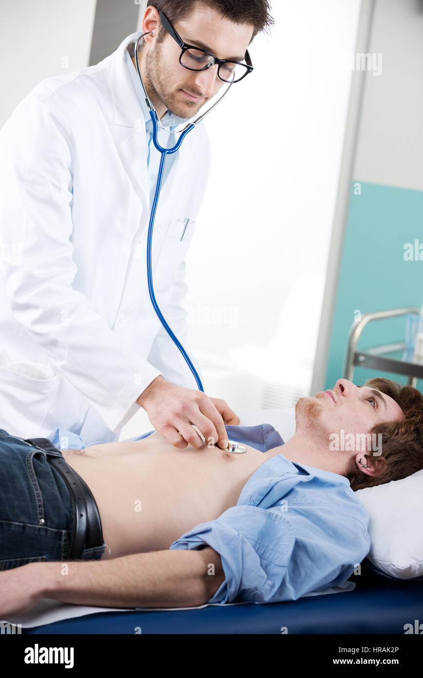 Arzt Überwachungsgerät sorgfältig ein Patient mit einem Stethoskop auf eine ärztliche Untersuchung-Tabelle. Stockfoto