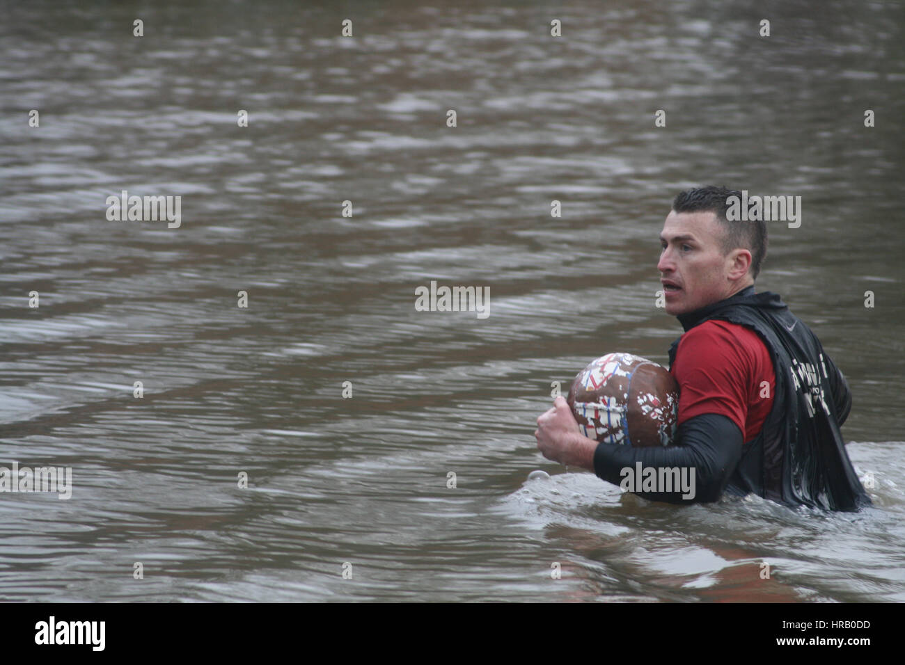 Ashbourne, Derbyshire, UK. Der jährliche Rumble zwischen Uppards und Downards, die Ashbourne Royal Fasching Footabll stattfinden wird. Im Wesentlichen ein riesiges Rugby Gedränge, die über die ganze Stadt stattfindet, müssen die Spieler Tor den Ball an einer der zwei Tore und welches Team man spielt hängt davon ab, ob Sie nach oben geboren wurden oder nach unten von der Henmore-Bach, der durch die Stadt schwärmen. Das ganze findet wieder statt morgen (1. März), Aschermittwoch. Spieler in den Henmore-Bach mit Ball. Stockfoto