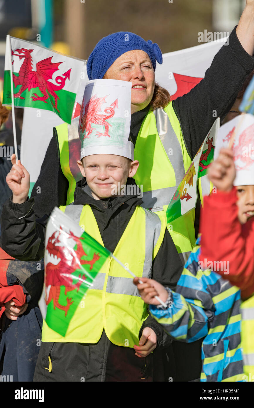 St. Davids Day Feierlichkeiten als Schulkinder Marsch durch die Stadt von Colwyn Bay, North Wales mit walisischen Fahnen und Narzissen Stockfoto