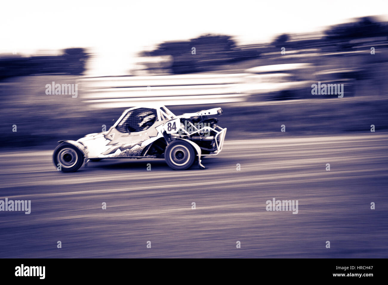 Buggy Rennen Auto bei hoher Geschwindigkeit, gedreht von der Seite mit Blur-Effekt und geringer Sättigung Stockfoto