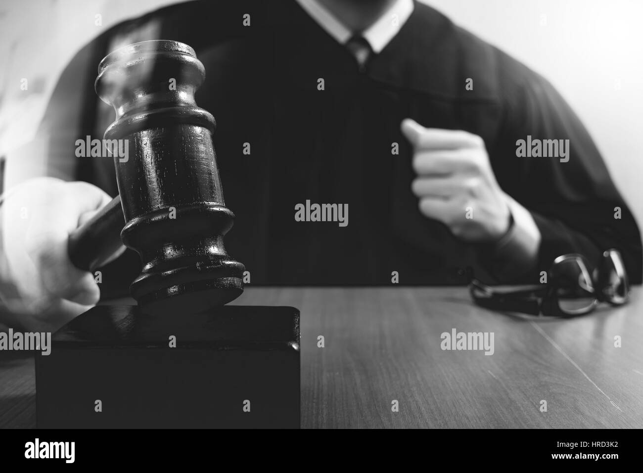 Recht und Gesetz-Konzept. Männlichen Richter in einem Gerichtssaal auffällig die Hammer, arbeiten mit digitalen Tablet Computer Docking-Tastatur auf Holztisch, schwarz und whi Stockfoto