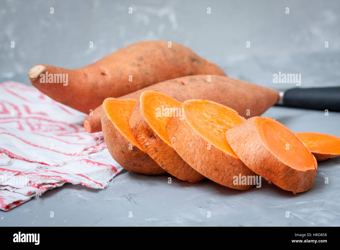 Roh in Scheiben geschnitten und ganze süße Kartoffeln auf einem dunklen Hintergrund rustikal. Stockfoto