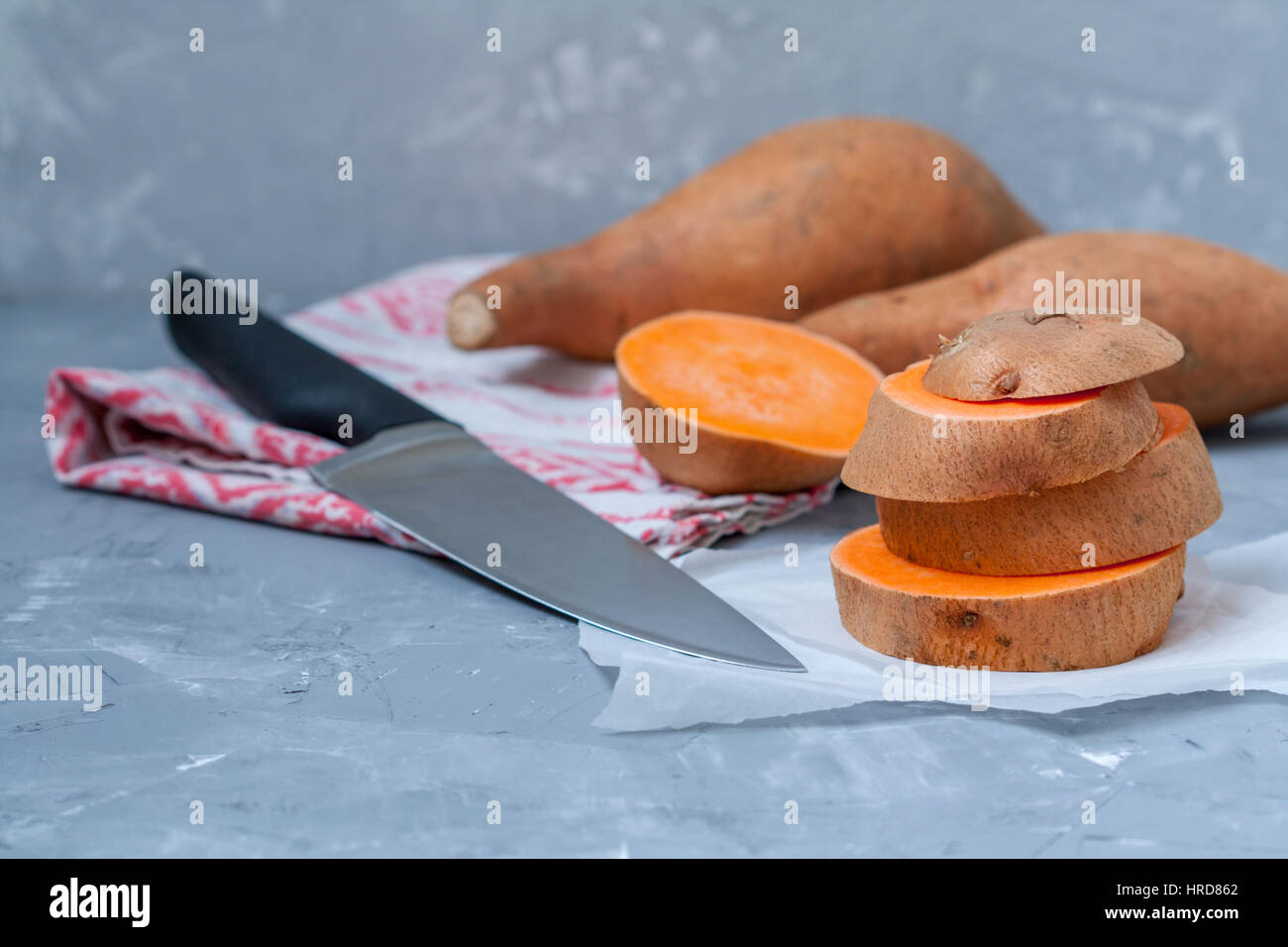 Roh in Scheiben geschnitten und ganze süße Kartoffeln auf einem dunklen Hintergrund rustikal. Stockfoto