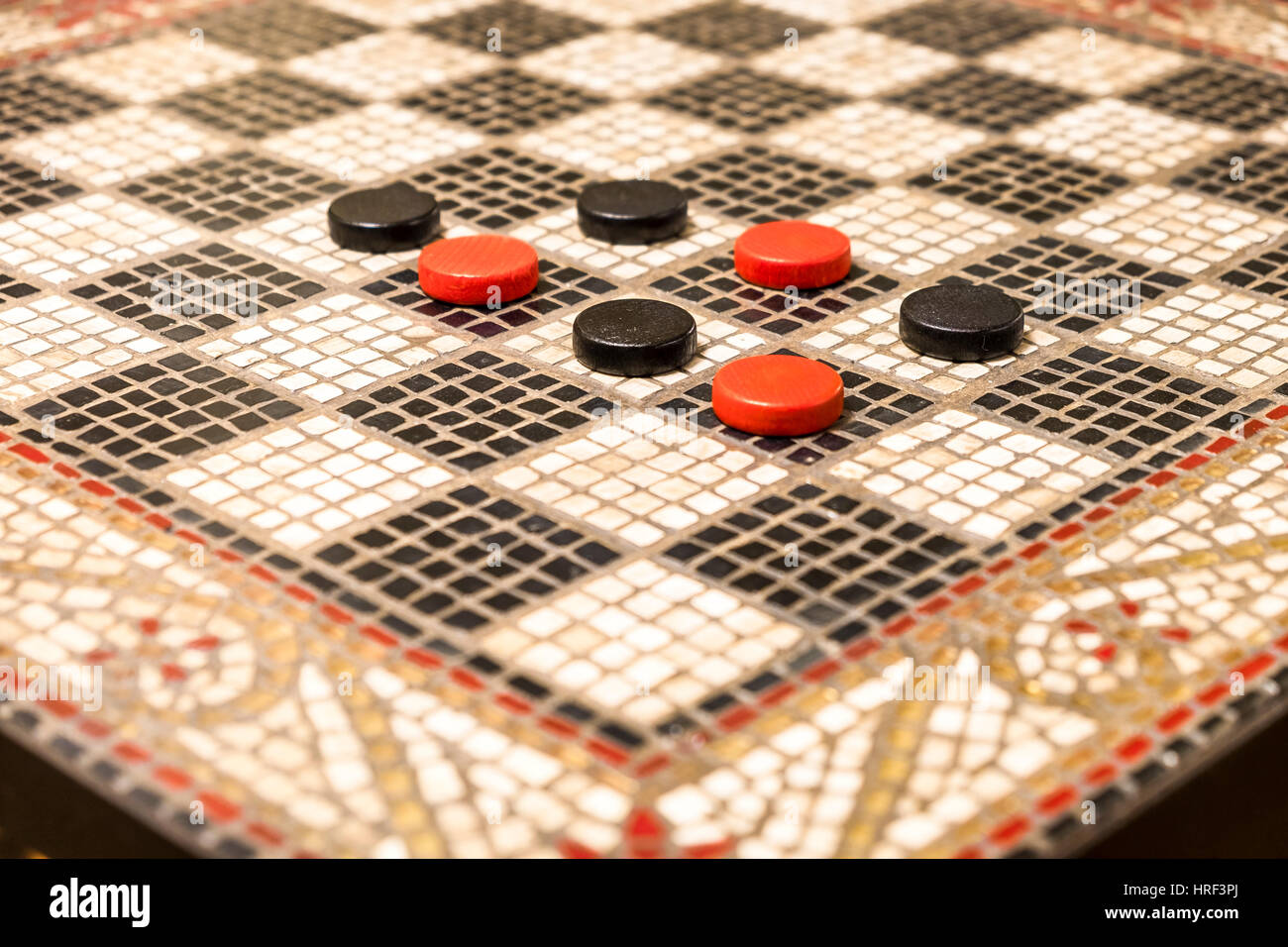 Rote und schwarze Checker Stücke auf einem Mosaik Stein Spieltisch. Stockfoto
