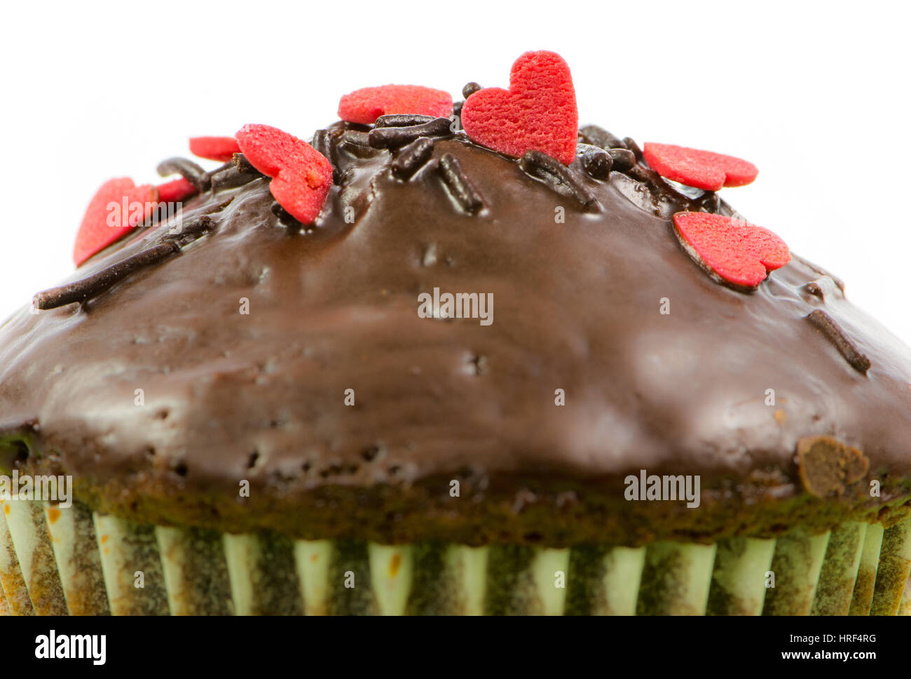 Nahaufnahme von einem isolierten Schoko-Muffin mit roten Zuckerherzen Stockfoto