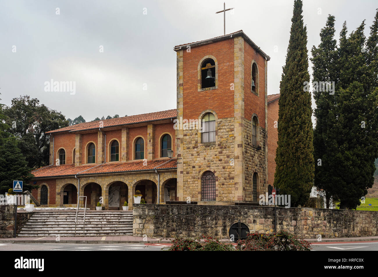 Kirche und Eiche am Kreisverkehr Eingang zur Stadt Cartes, Kantabrien Spanien. Stockfoto