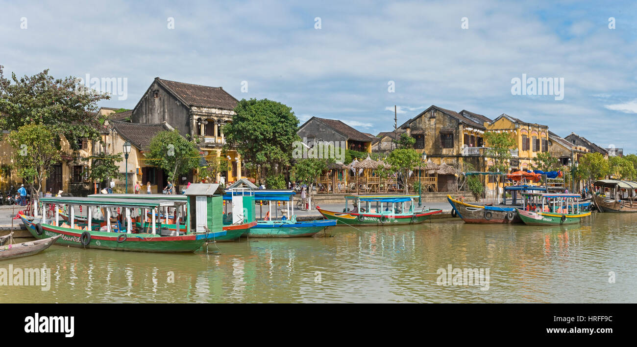 Eine Ansicht Inl Hoi an eine alte Stadt mit hölzernen Touristen- und Angelboote/Fischerboote am Thu Bon Fluss neben der Cau An Hoi an Brücke an einem sonnigen Tag mit blauem Himmel. Stockfoto