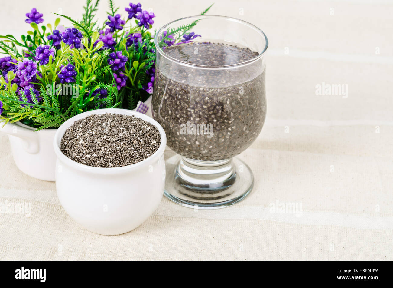Trocknen Sie Chai Samen, super Essen, getränkt in klarem Glas des Wassers auf der Tischdecke. Stockfoto