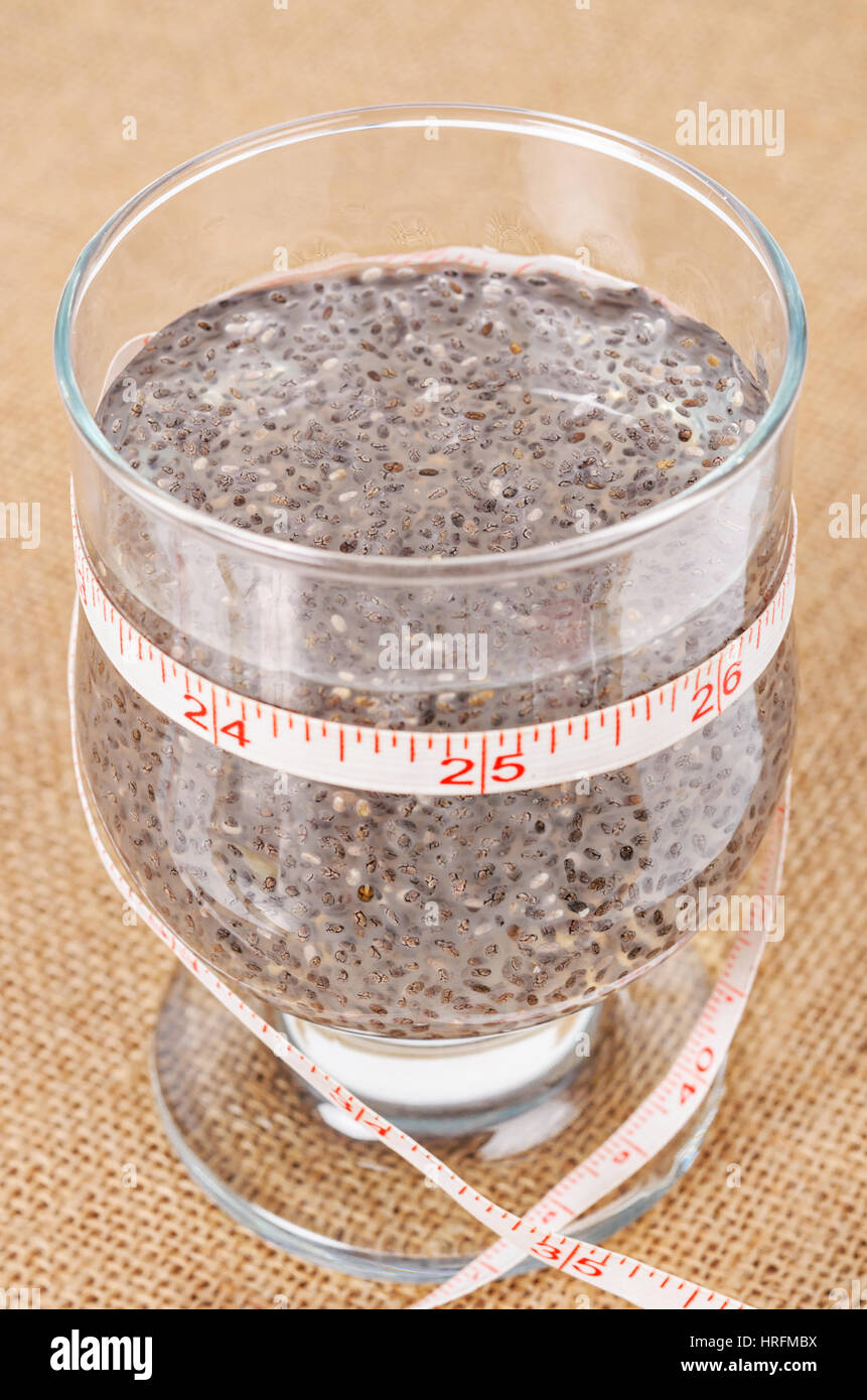 Chai Samen, super Essen, getränkt in klarem Glas mit Wasser und Maßband um ihn herum auf Sack Hintergrund laufen. Stockfoto