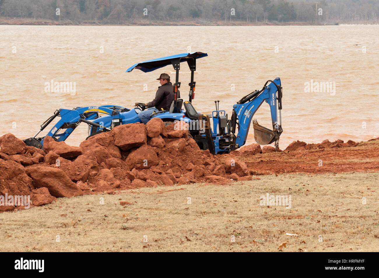 Ein Arbeiter zieht Schmutz und Rock mit einem Wald Groundbreaker BH70-X Baggerlader zu untermauern die Ufer des Sees von Arcadia. Oklahoma, USA. Stockfoto