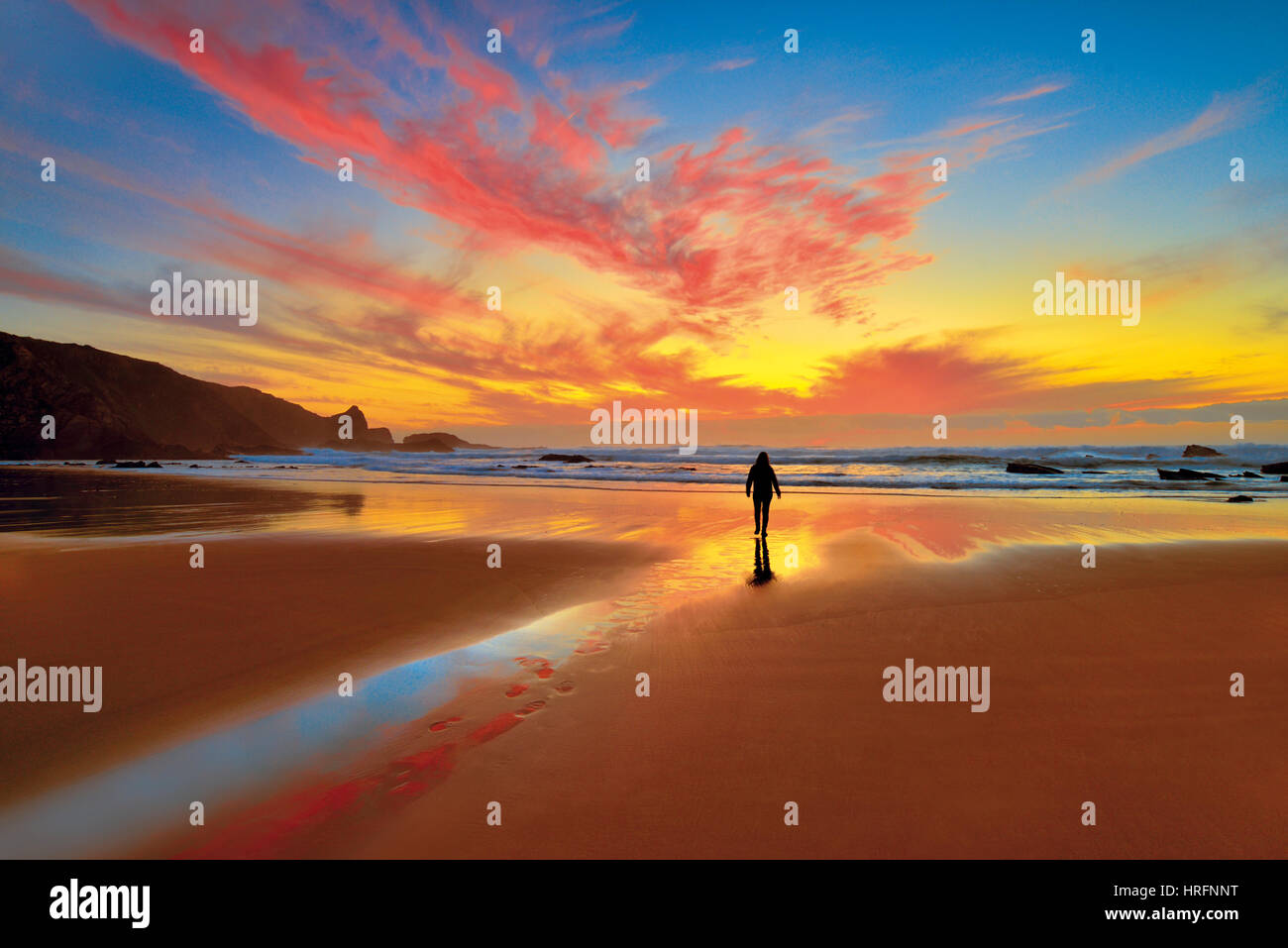 Malerischen Sonnenuntergang mit Frau zu Fuß auf Ebbe Strand Stockfoto