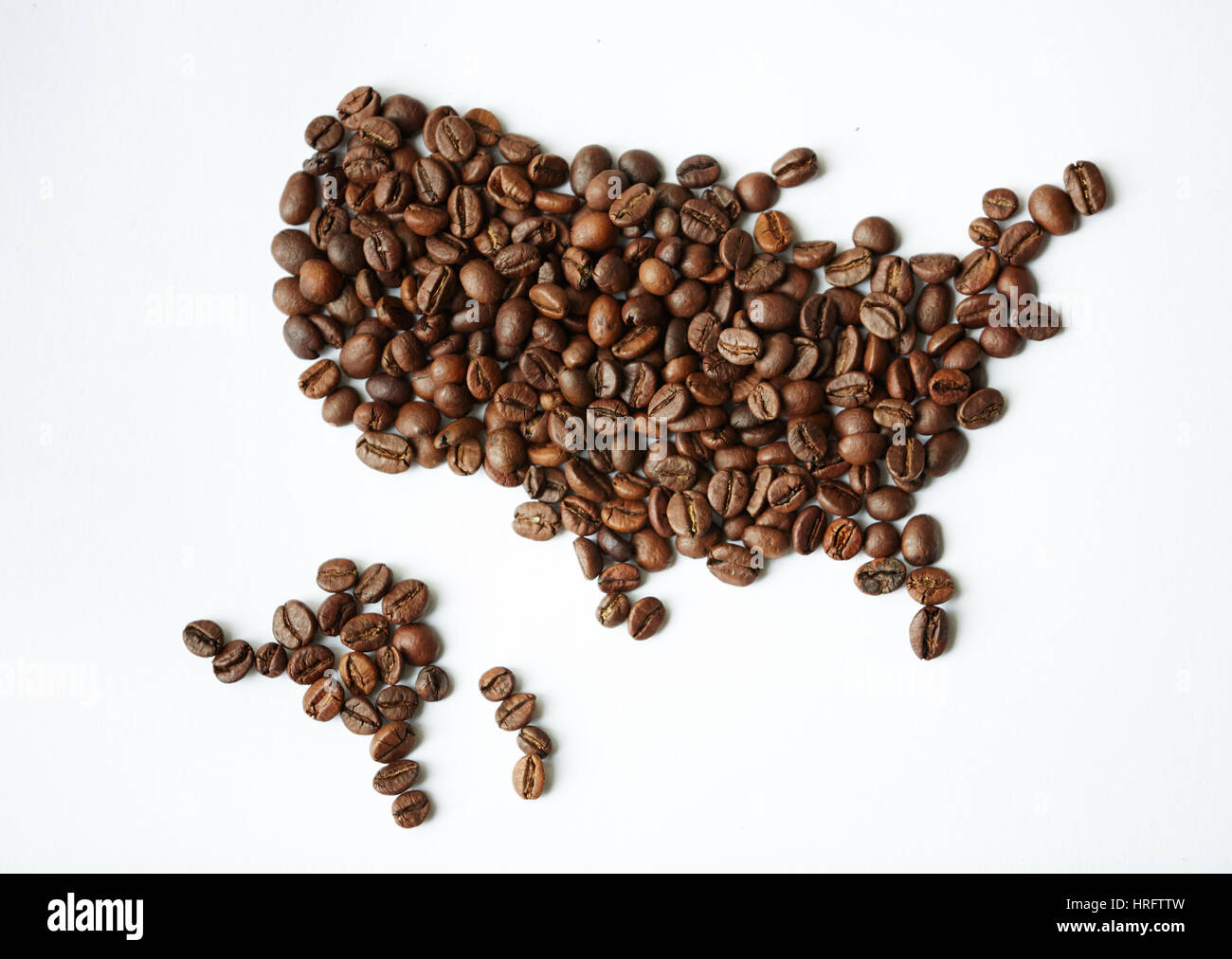 Closeup über Ansicht gedreht: Heap reichen braun frisch gerösteten Kaffee Samen auf weißen Tisch in Form der Weltkarte mit Kontinenten verstreut Stockfoto