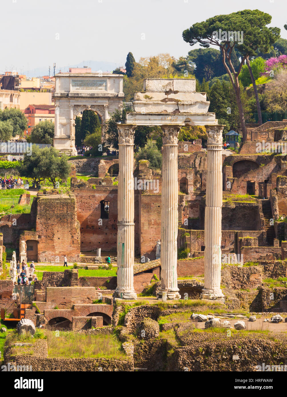 Rom, Italien.  Das Forum Romanum. Die drei Säulen der Tempel des Castor und Pollux.  Der Titus-Bogen im Hintergrund. Das Forum ist Teil des Hi Stockfoto