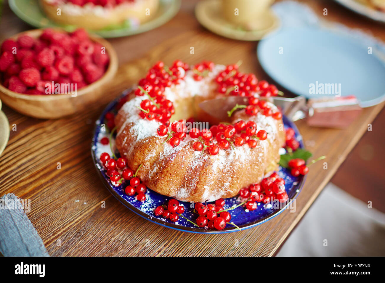 Nahaufnahme des frisch gebackenen Kuchen mit roten Johannisbeeren und Puderzucker auf Holztisch liegend Stockfoto