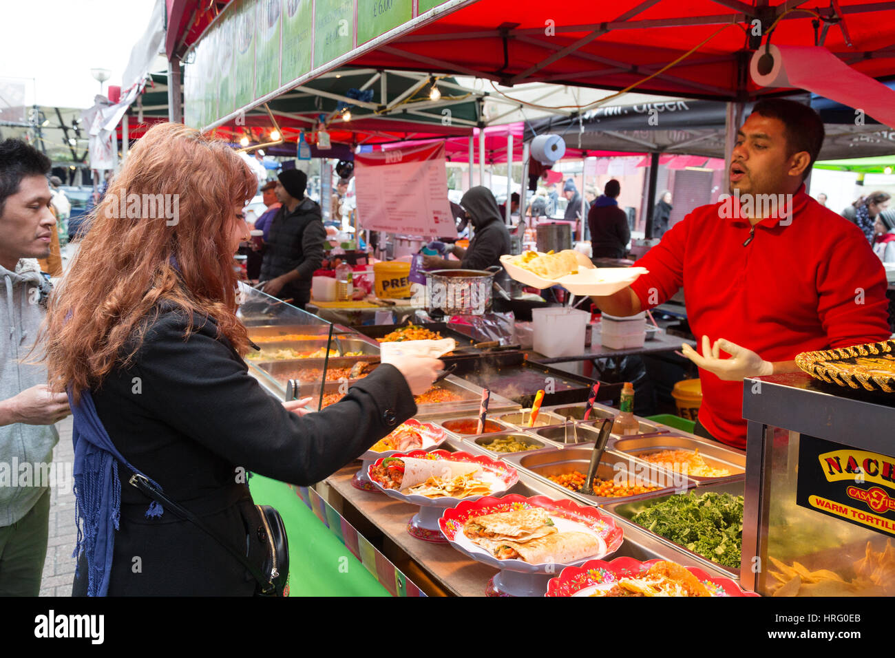 Streetfood; Straßenmarkt; -Eine Frau kauft mexikanisches Essen aus einer Garküche, Portobello Road Market, Portobello Road, Notting Hill, London UK Stockfoto