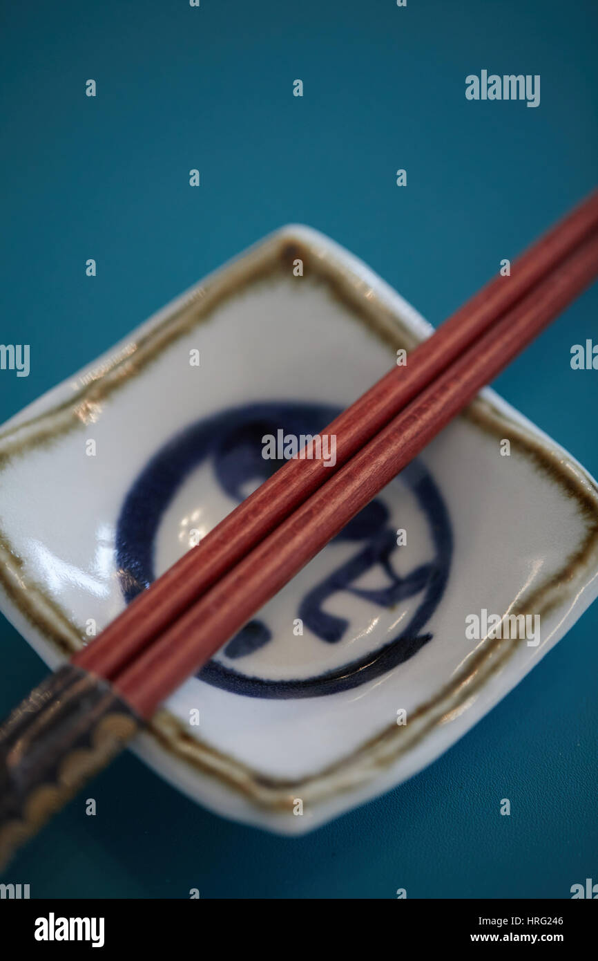 Chinesische Stäbchen auf einen kleinen traditionellen Teller, Stockfoto