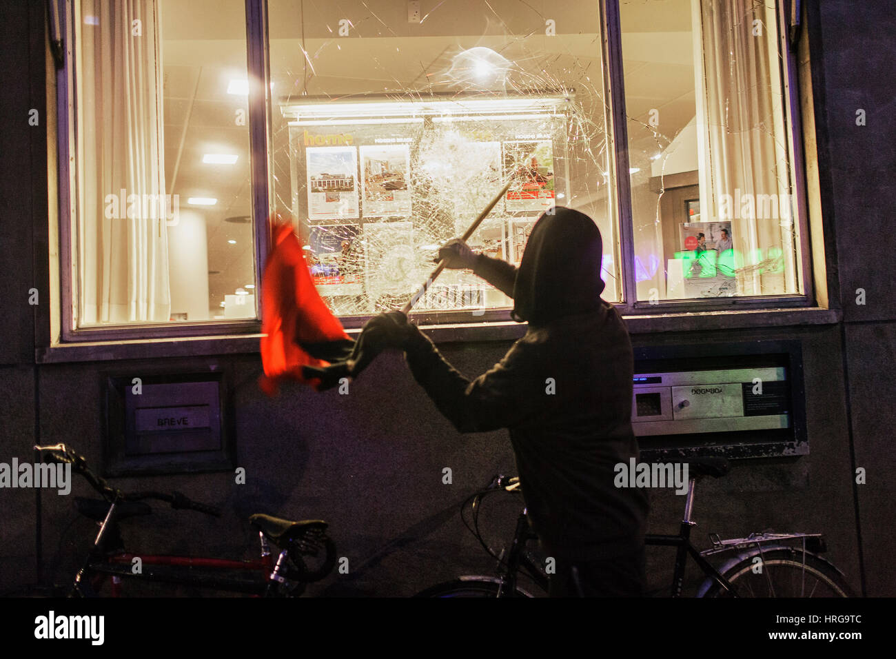 Kopenhagen, Dänemark. 1. März 2017. Linke Aktivisten dauerte die Straßen von Kopenhagen zehn Jahre nach dem Abriss des Jugendhaus Ungdomshuset bei Jagtvej 69. Unter der Aussage "der Kampf geht weiter, nichts vergessen, nichts verziehen" die Aktivisten kollidierte mit der Polizei während des Marsches. Hier greift ein Aktivist eine Bank die Fenster zerschlagen. Bildnachweis: Gonzales Foto/Alamy Live-Nachrichten Stockfoto