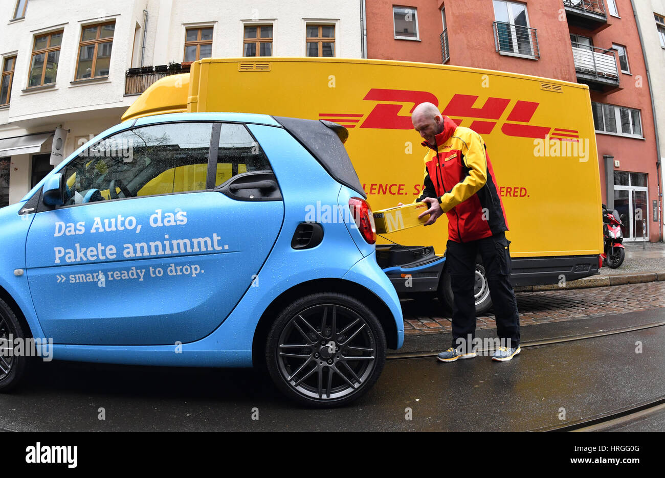 Berlin, Deutschland. 2. März 2017. Ein DHL-Mitarbeiter legt eine Paket im Kofferraum eines Smart Autos in Berlin, Deutschland, 2. März 2017. Beim Versandunternehmen läuft ein Pilotprojekt, in welche Smart Besitzer Pakete zu ihren Autos haben können. Um das Angebot zu nutzen, müssen Besitzer registrieren mit DHL und der Automobilhersteller ihren Smart mit der nötigen Technologie auszurüsten. Berlin ist die vierte große Stadt in Deutschland, in denen der Dienst getestet wird. Foto: Paul Zinken/Dpa/Alamy Live News Stockfoto