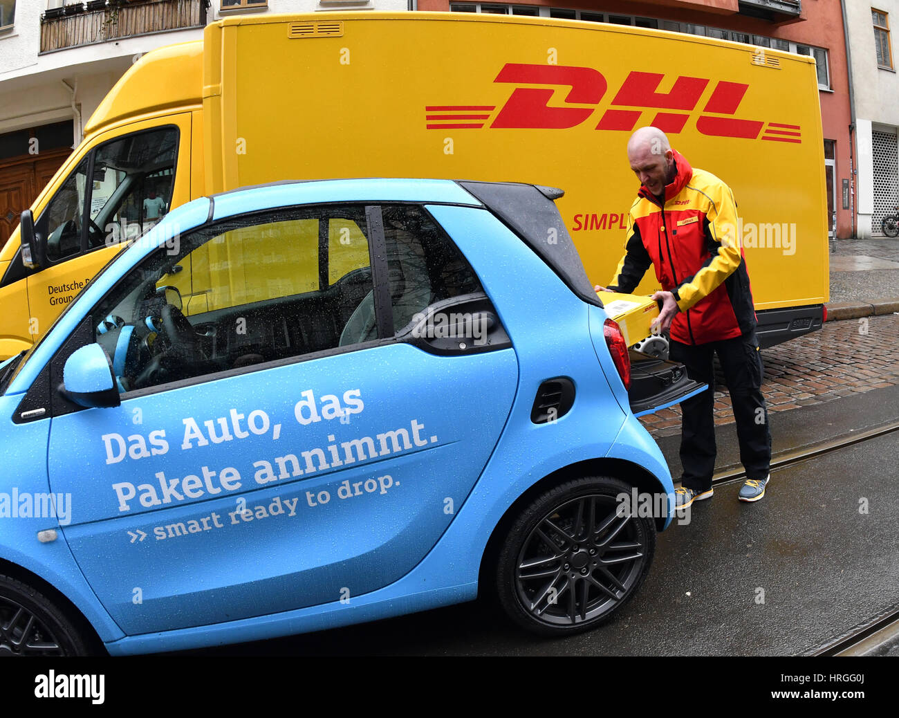 Berlin, Deutschland. 2. März 2017. Ein DHL-Mitarbeiter legt eine Paket im Kofferraum eines Smart Autos in Berlin, Deutschland, 2. März 2017. Beim Versandunternehmen läuft ein Pilotprojekt, in welche Smart Besitzer Pakete zu ihren Autos haben können. Um das Angebot zu nutzen, müssen Besitzer registrieren mit DHL und der Automobilhersteller ihren Smart mit der nötigen Technologie auszurüsten. Berlin ist die vierte große Stadt in Deutschland, in denen der Dienst getestet wird. Foto: Paul Zinken/Dpa/Alamy Live News Stockfoto