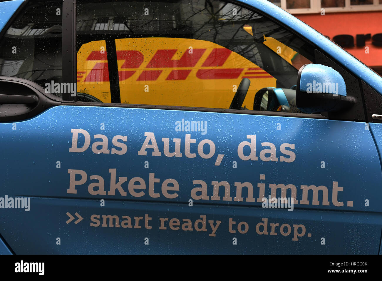 Berlin, Deutschland. 2. März 2017. Ein DHL-Mitarbeiter legt eine Paket im Kofferraum eines Smart Autos in Berlin, Deutschland, 2. März 2017. Beim Versandunternehmen läuft ein Pilotprojekt, in welche Smart Besitzer Pakete zu ihren Autos haben können. Um das Angebot zu nutzen, müssen Besitzer registrieren mit DHL und der Automobilhersteller ihren Smart mit der nötigen Technologie auszurüsten. Berlin ist die vierte große Stadt in Deutschland, in denen der Dienst getestet wird. Foto: Paul Zinken/Dpa/Alamy Live News Stockfoto