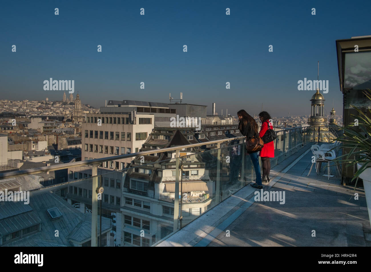 2 Mädchen in die atemberaubende Aussicht auf die Dächer von Paris an einem sonnigen Wintertag mit Sacré-Coeur in der Ferne genießen. Stockfoto