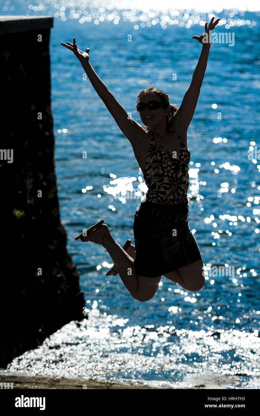 Model freigegeben, Silhouette Einer Springenden Frau bin Seeufer, Italienisch - Silhouette einer springenden Frau am Meer Stockfoto