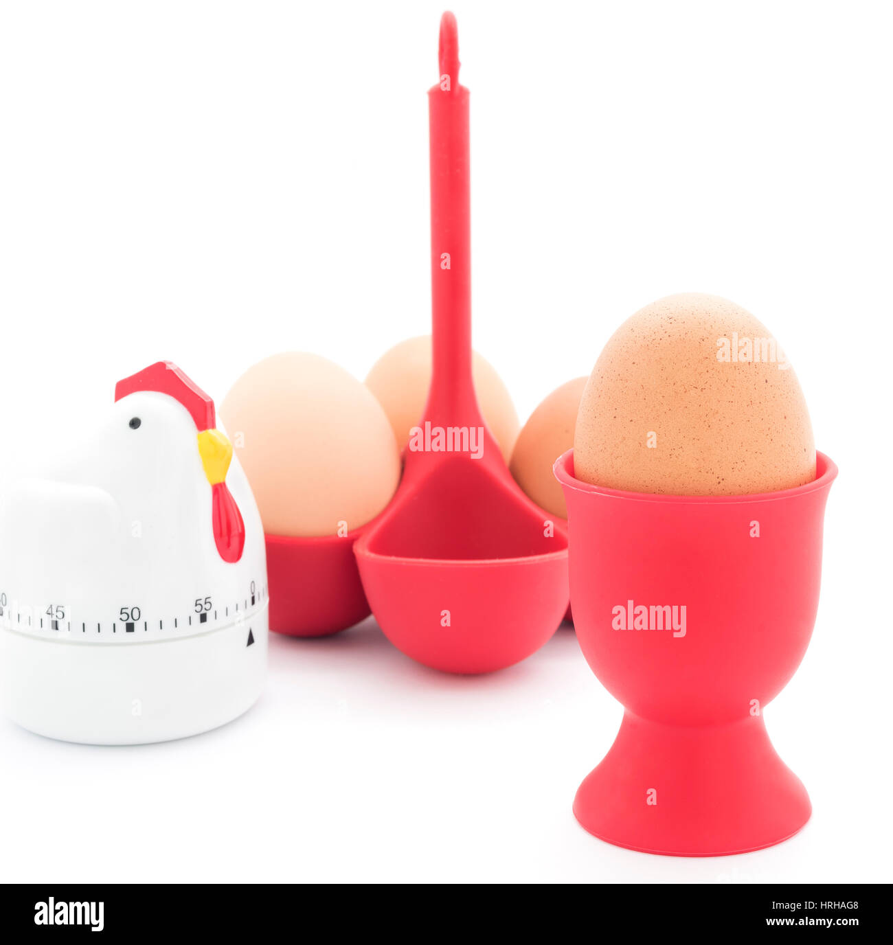 Gekochte Hühnereier in ein rotes Ei Cup und rot-Halter mit Eieruhr isoliert auf weiss. Stockfoto