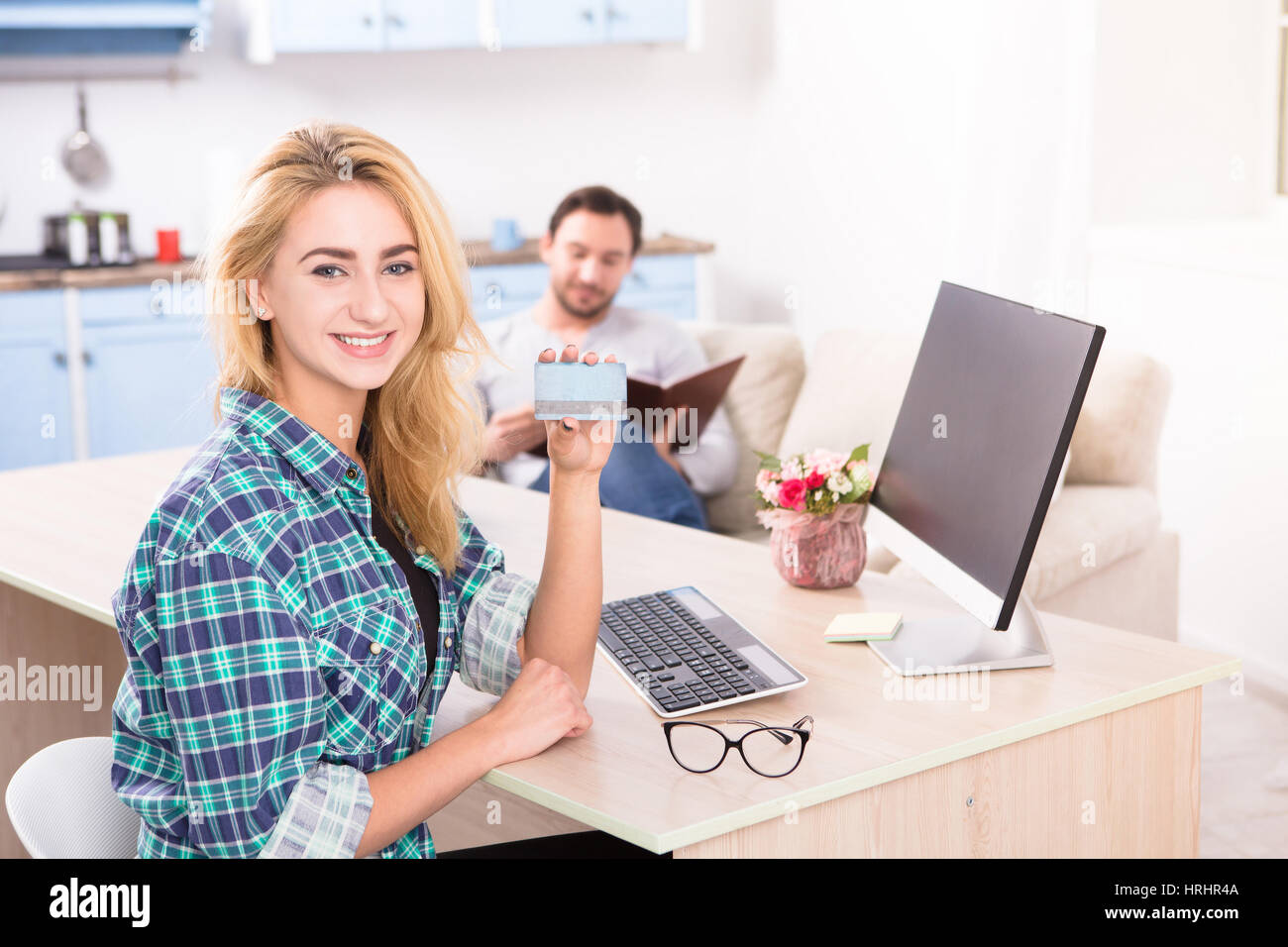 Getönten fröhliche junge Dame mit Kreditkarte, Kamera. Hübsche Frau am Tisch mit Computer auf lächelnd. Büroeinrichtung. Geschäft Konz Stockfoto