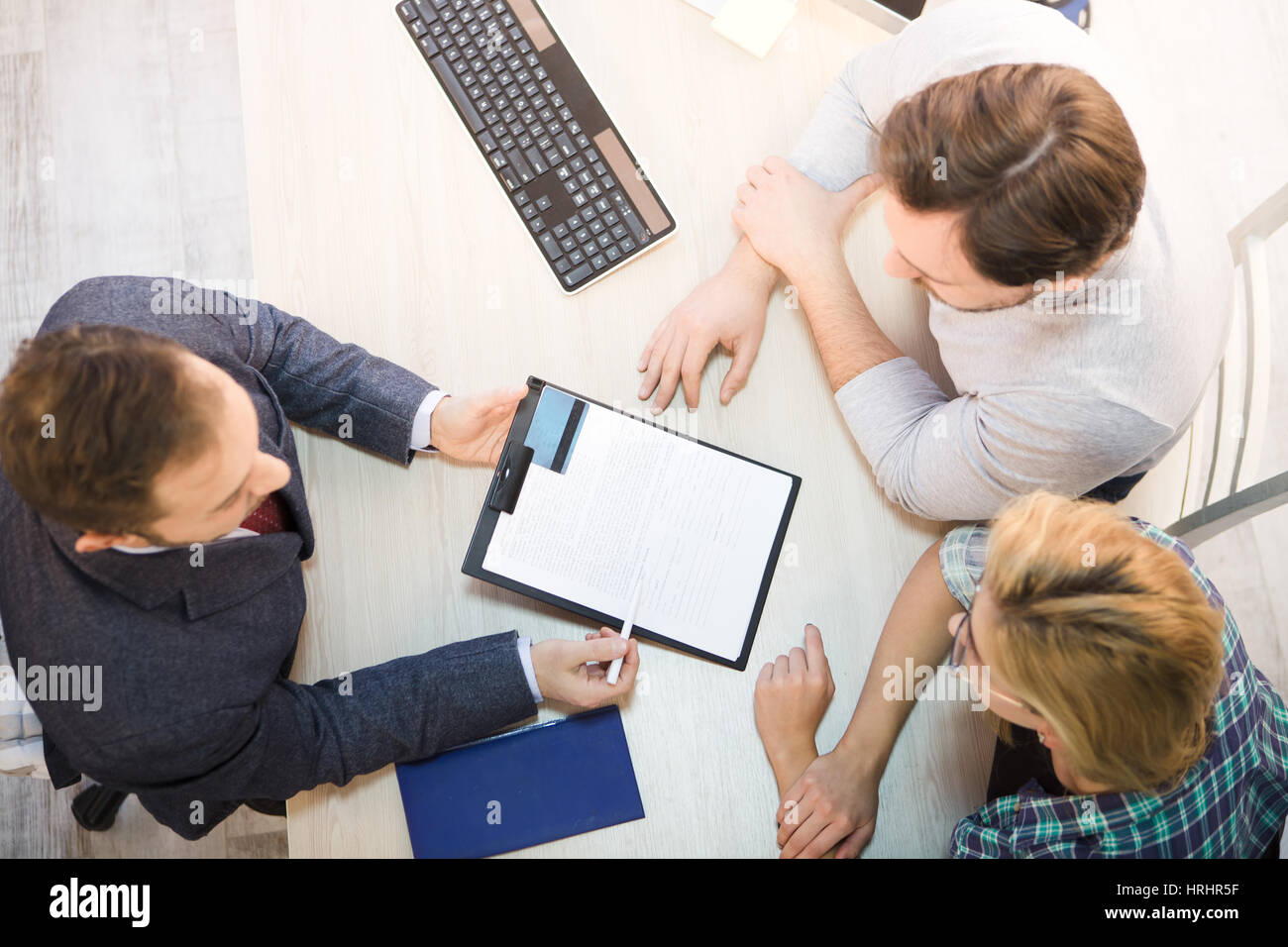 Top getönten Verkäufer kommunizieren mit jungen Paar und bieten entsprechende Vereinbarung oder einen Vertrag für die erste Kreditkarte für ihre Zwecke. Website Stockfoto