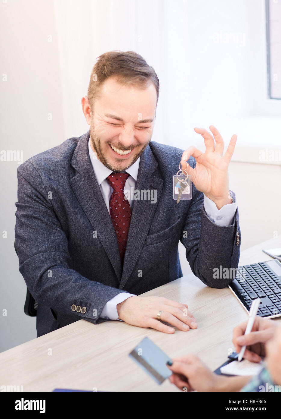 Getönten glücklich sales Manager hält Schlüssel von der neuen Wohnung. Glücklich lächelnden Manager im Business-Anzug bietet entsprechende Abkommen oder Verträgen. Stockfoto