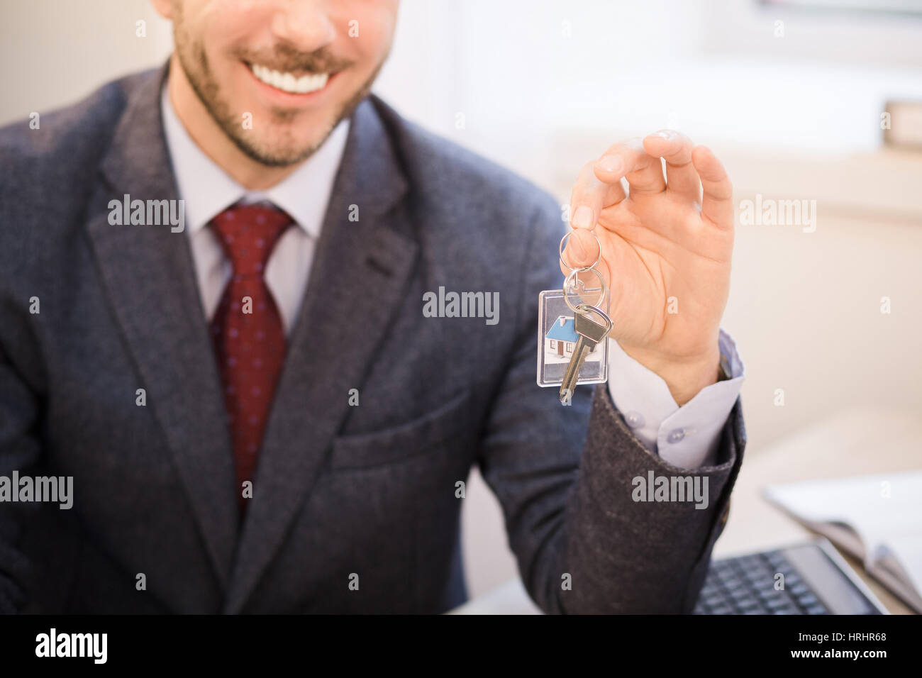 Getönten Bild eines schönen mittleren gealterten Immobilienmakler beschnitten in klassischen Anzug Taste aus neue Wohnung für seine Kunden und lächelnd beim Sitzen im Büro. Stockfoto
