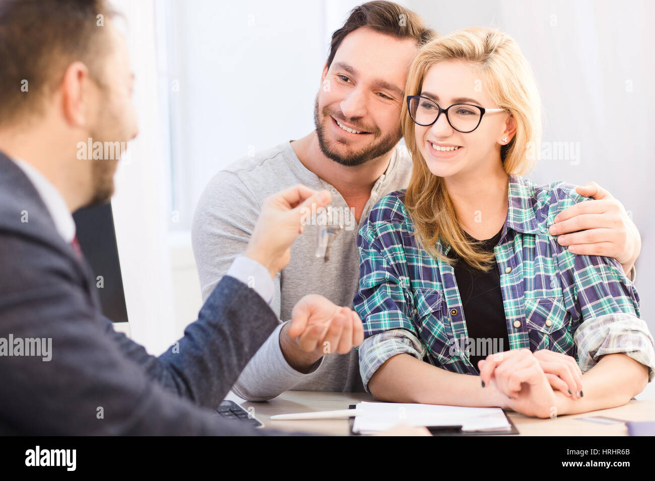 Getönten sales Manager für junge Paar in Liebe zu geben. Glückliches Paar lächelnd nach Unterzeichnung der Vereinbarung oder einen Vertrag zum Kauf oder Verkauf. Autohaus c Stockfoto