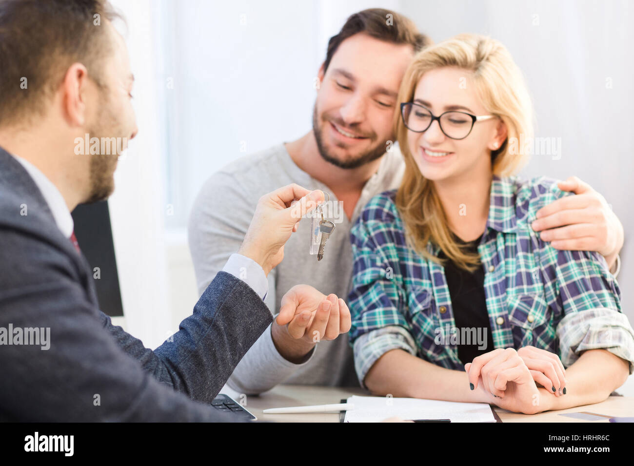 Autohaus-Konzept. Bank-Konzept. Getönten sales Manager bereit, um Schlüssel zu junge Paar in der Liebe nach der Unterzeichnung der Vereinbarung oder einen Vertrag zum Kauf oder Stockfoto
