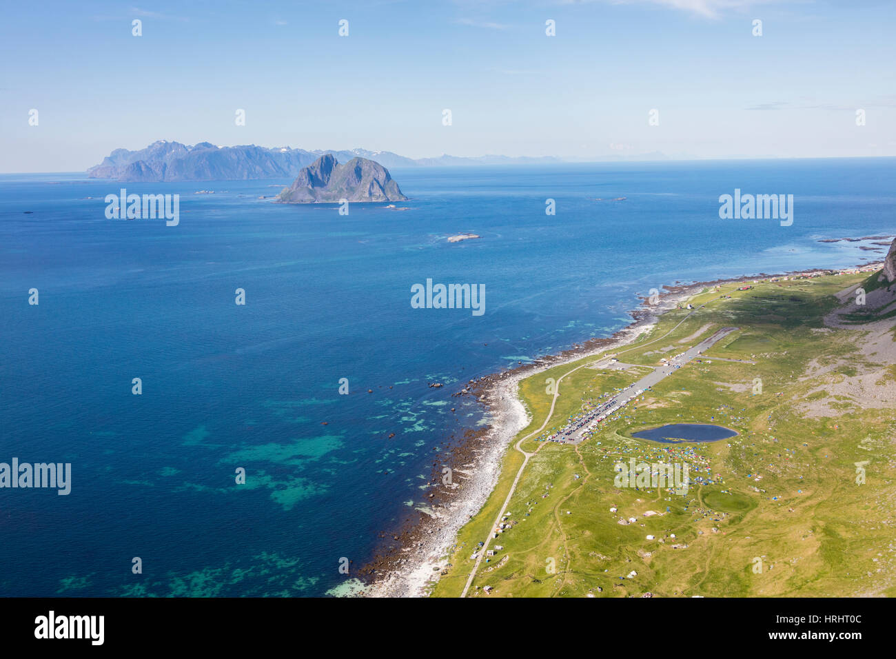 Zelten auf den grünen Wiesen umgeben von blauen See und Meer, Vaeroy Insel, Nordland Grafschaft, Lofoten Inselgruppe, Norwegen Stockfoto