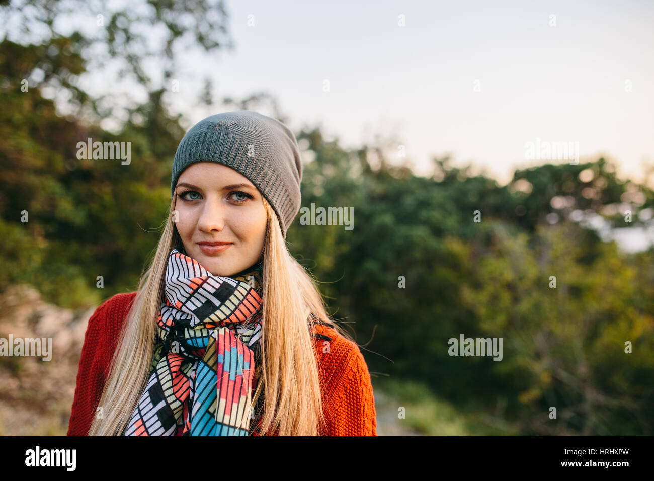 Porträt von eine schöne junge blonde Frau in Hut, rote Pullover im Freien auf dem Hintergrund des Waldes Stockfoto