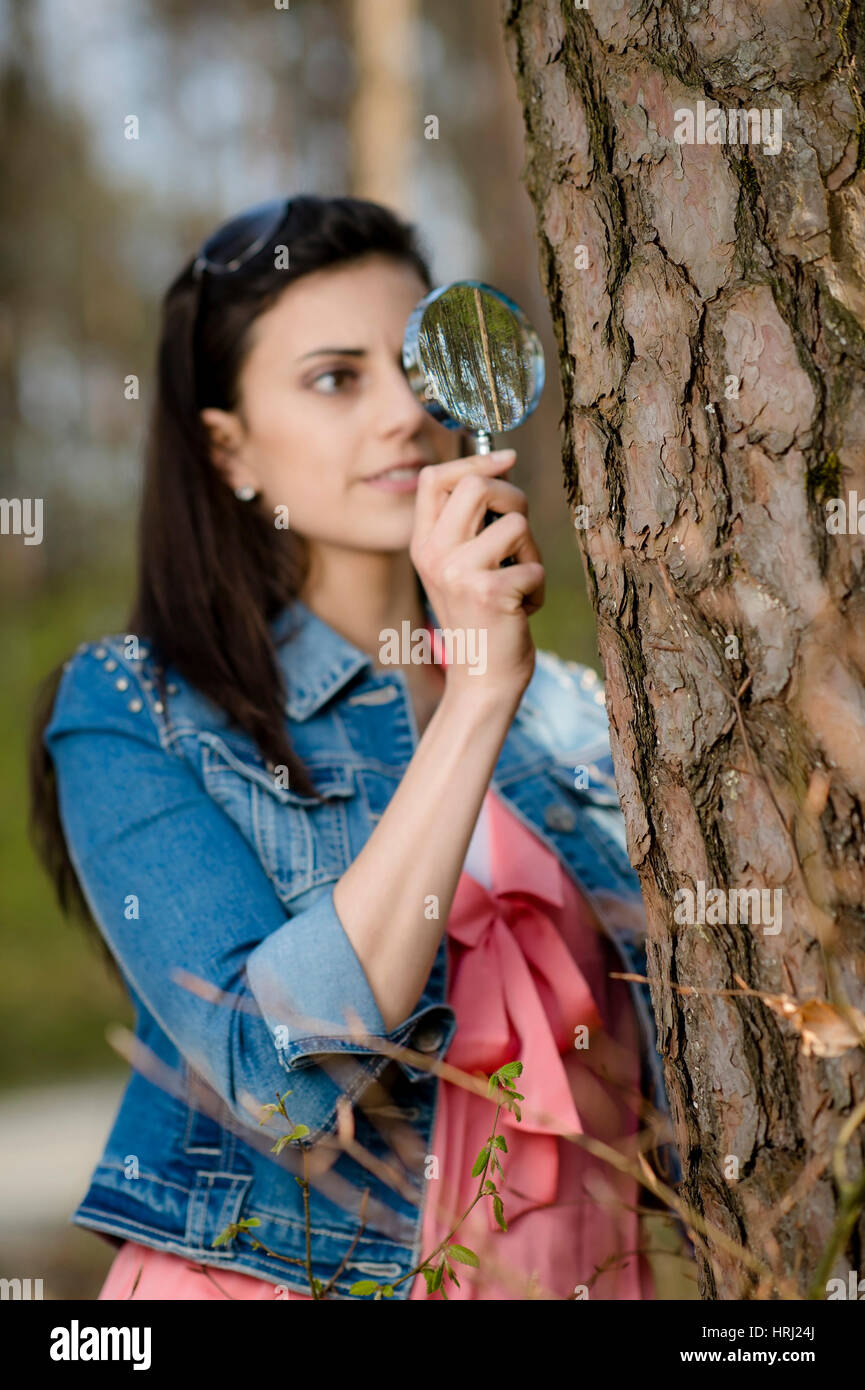 Frau Betrachtet Baumrinde Durch die Lupe - Frau schaut an Baumrinde durch die Lupe Stockfoto