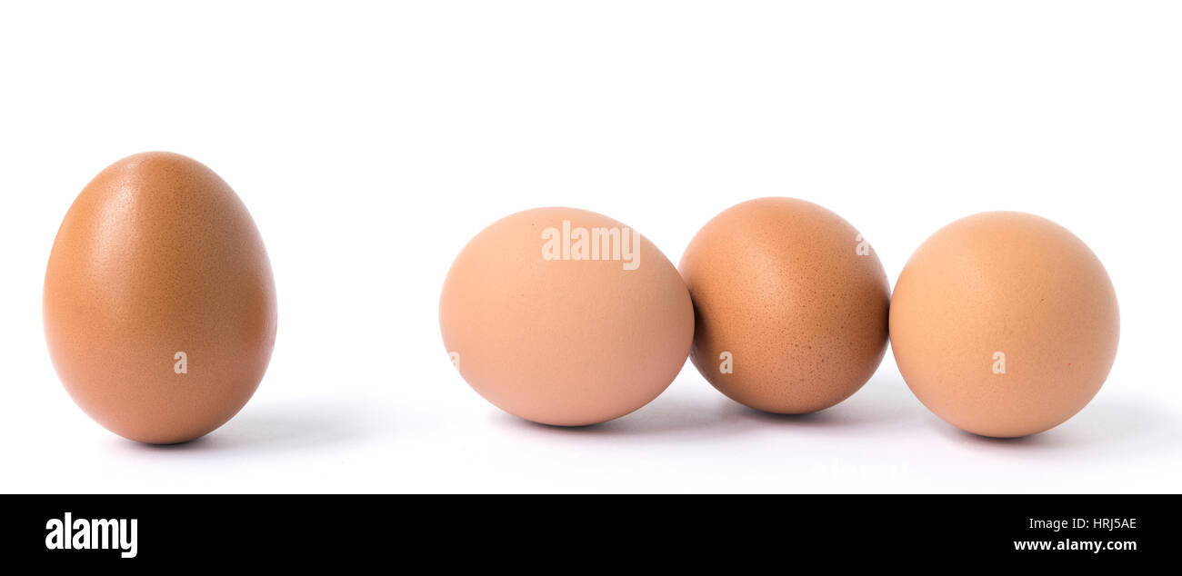 Große braune Hühner-Ei und eine Gruppe von drei Eiern isoliert auf weiss. Stockfoto