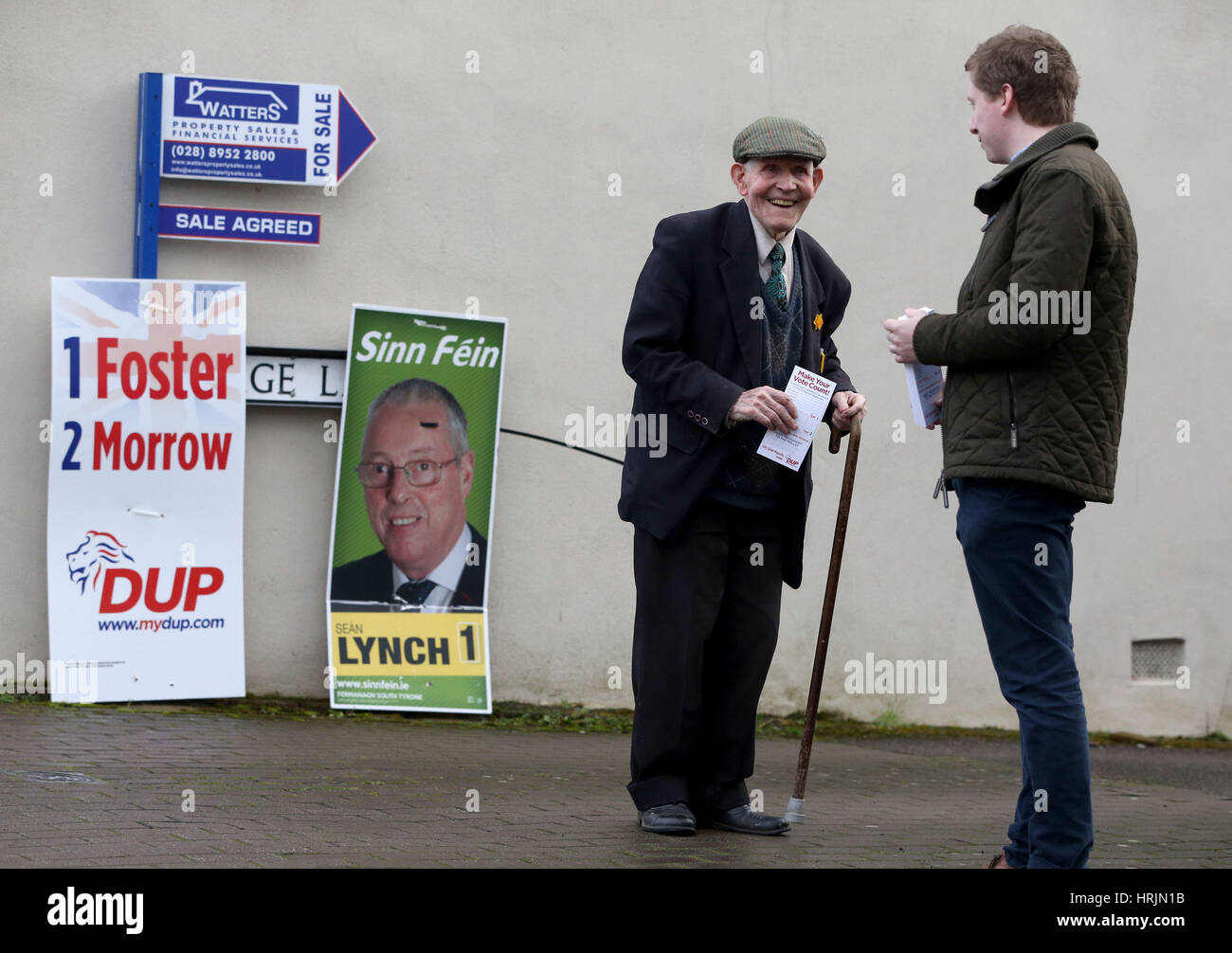 Eine Mann wird angesprochen durch einen Akquisiteur auf seinem Weg ins Wahllokal am Brookeborough Grundschule, Co Fermanagh, nach die Wahlen in die Northern Ireland Assembly Wahlen eröffnet. Stockfoto