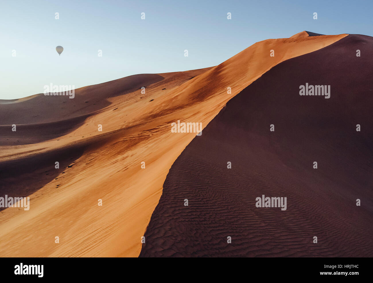 Eine Sanddüne in der Wüste, mit einem Heißluftballon in den blauen Himmel über. Stockfoto