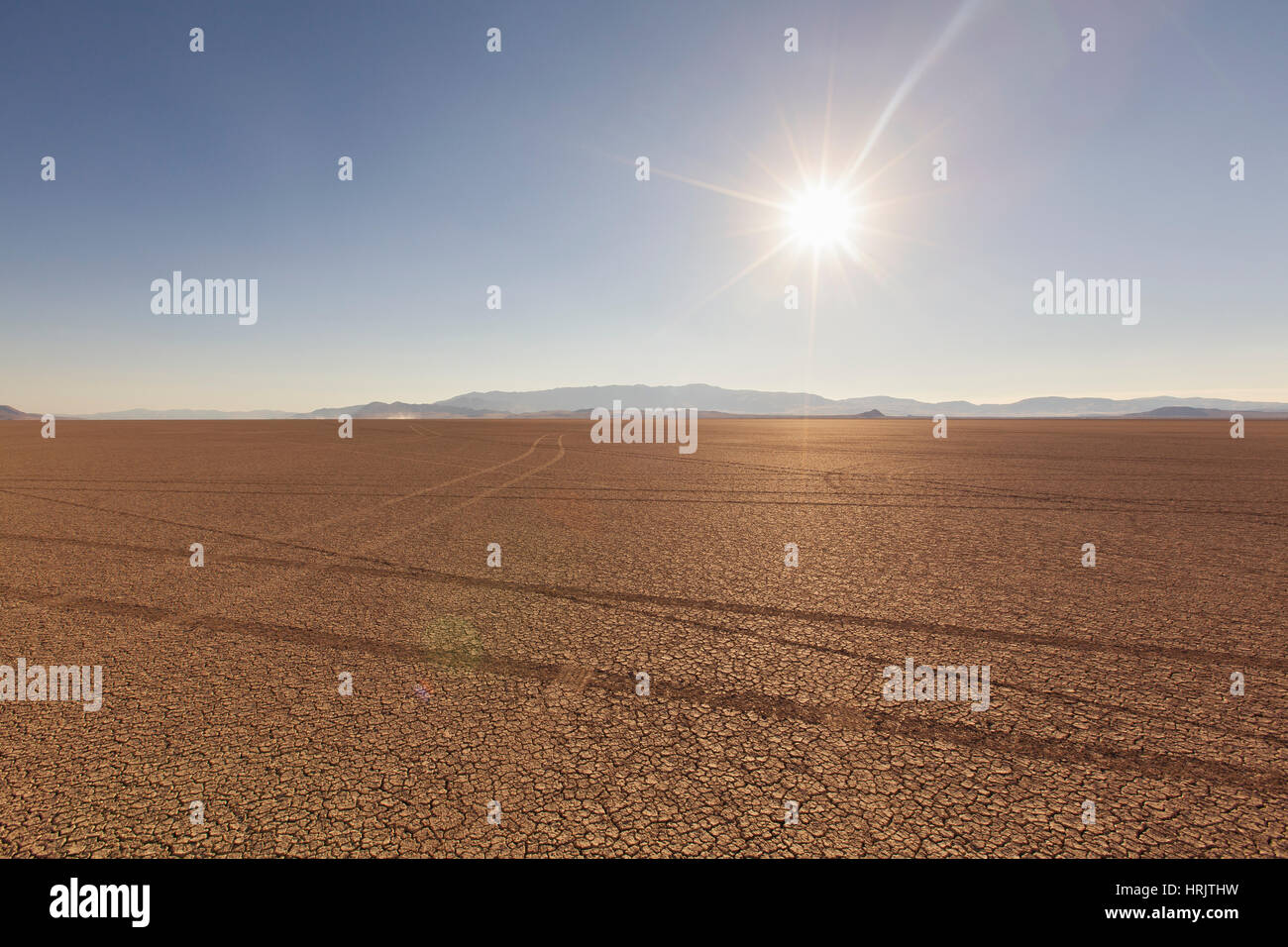 Reifenspuren in eine Wüstenlandschaft mit Bergen in der Ferne. vor einem blauen Himmel. Stockfoto