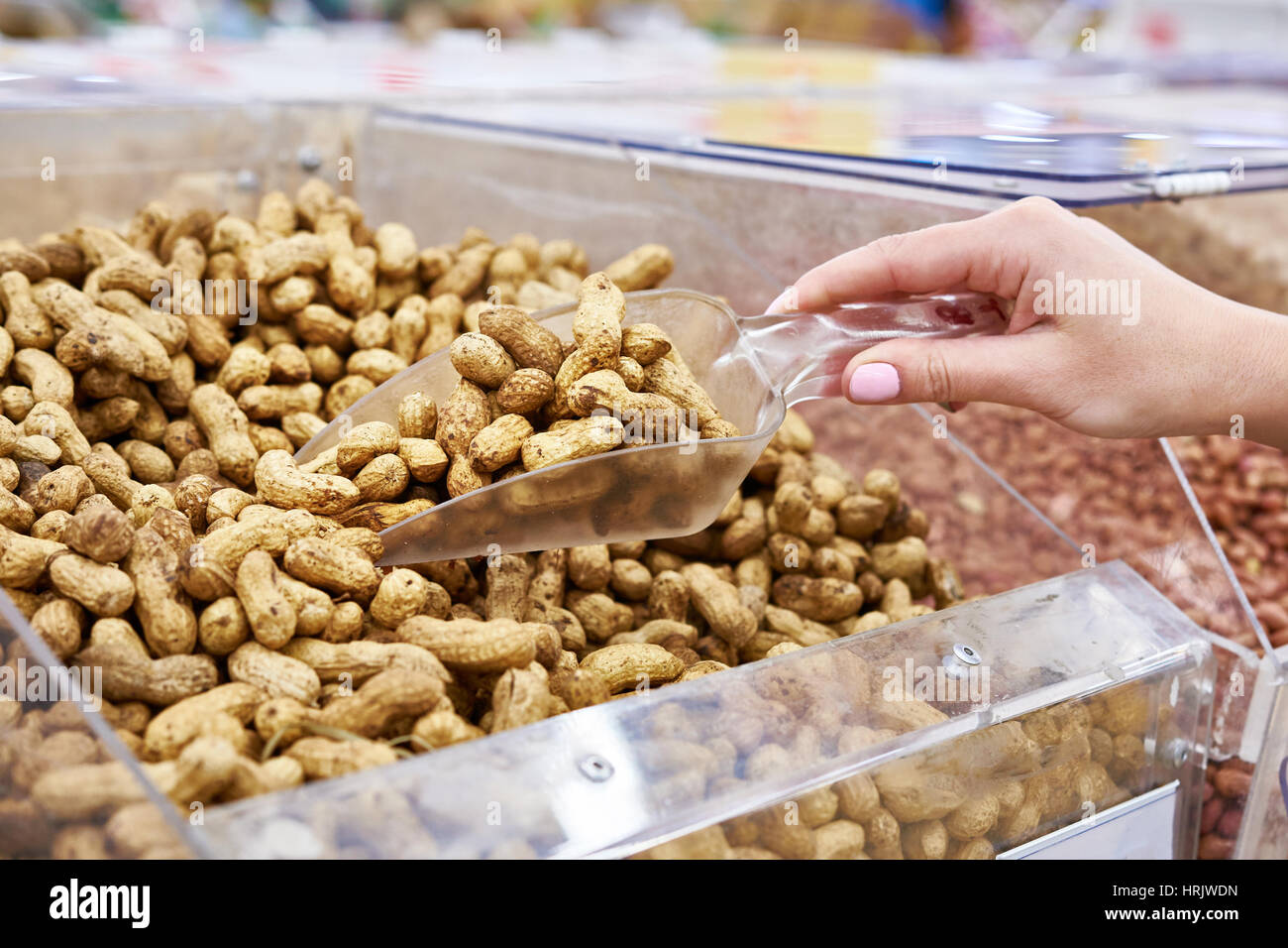 Käufer mit Schaufel nimmt die Erdnüsse in der Filiale Stockfoto