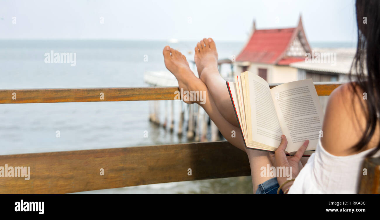 Mädchen lesen ein Buch auf dem Balkon mit Blick aufs Meer Stockfoto